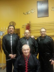 Four instructors standing together before the weapons wall