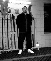 Shifu Jack standing at attention before the weapons rack, black and white photo